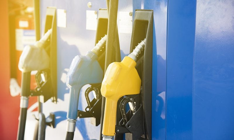 Three fuel pumps on sunny fuel station forecourt.