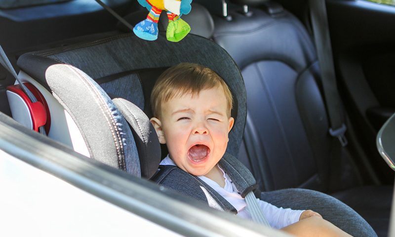 Image Caption Parents struggle to get their kids into the car.