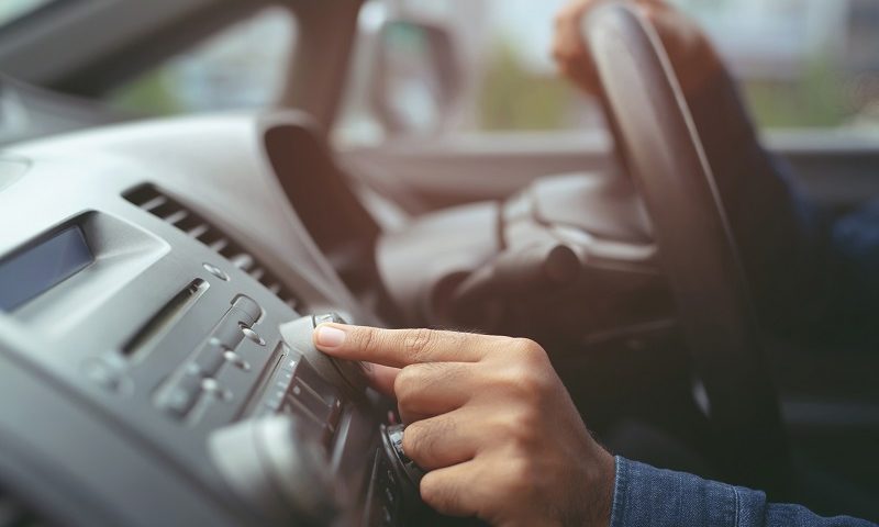 Driver turns volume dial on car radio