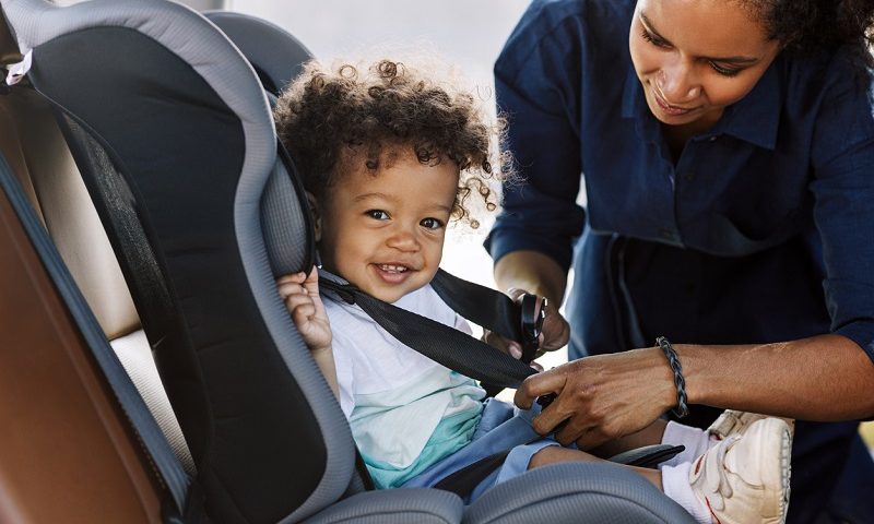 Parent strapping child into car seat.