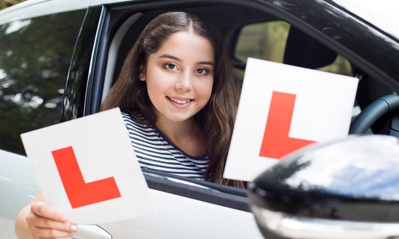 Learner driver holding L-plates.