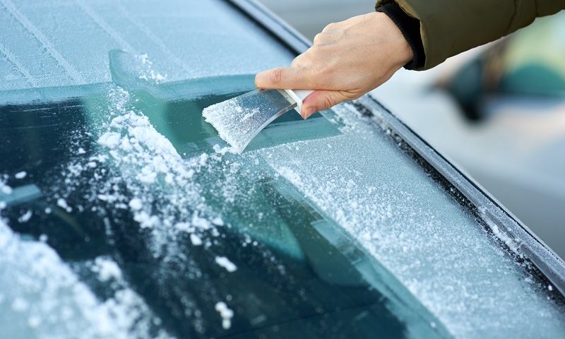 Scraping ice off the windshield.