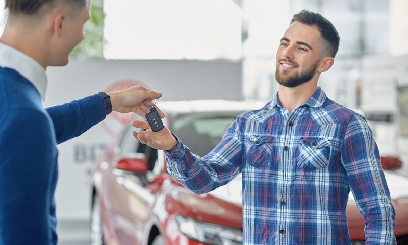 Car salesman handing over car key to customer