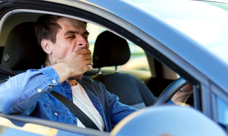 A man yawns while driving