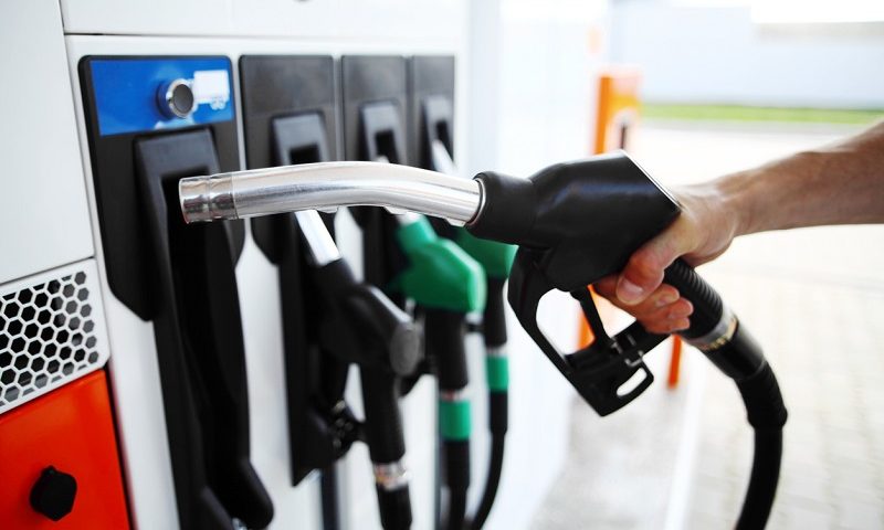 A driver holds a fuel pump at a service station