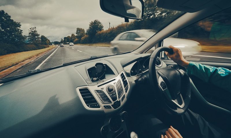 A motorist driving down a busy road on an English single carriageway