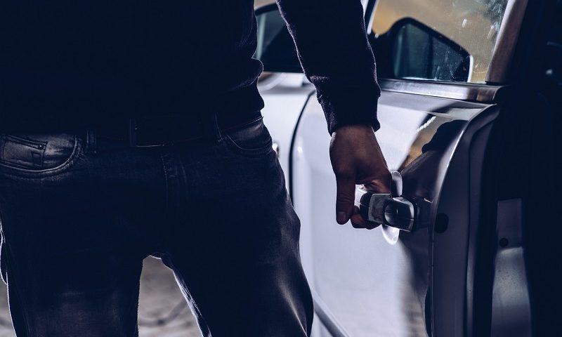 Car thief opening the doors of a stolen car