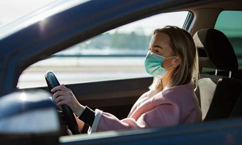 Woman wears Covid-19 mask while driving.