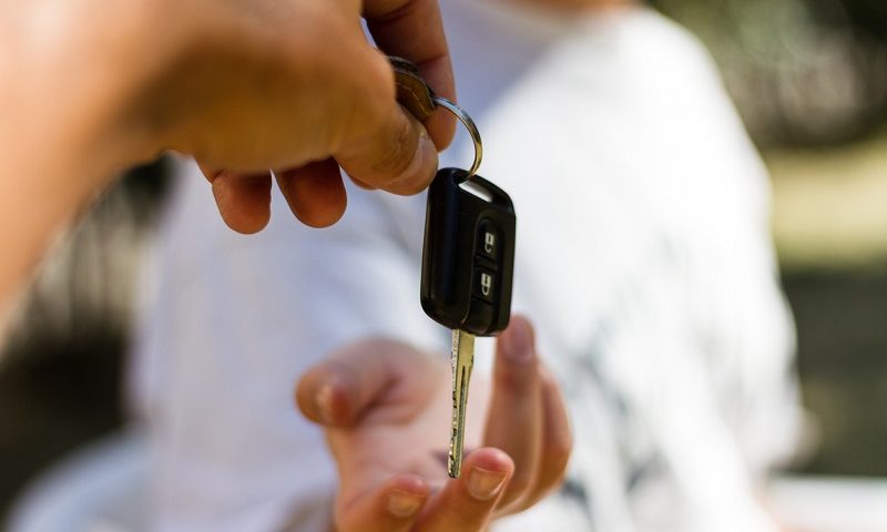 A car key being handed over to a buyer