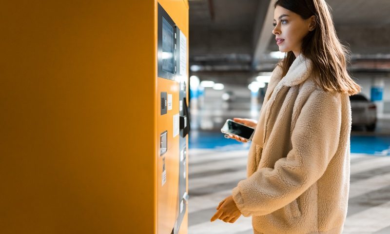 Young woman paying for car parking