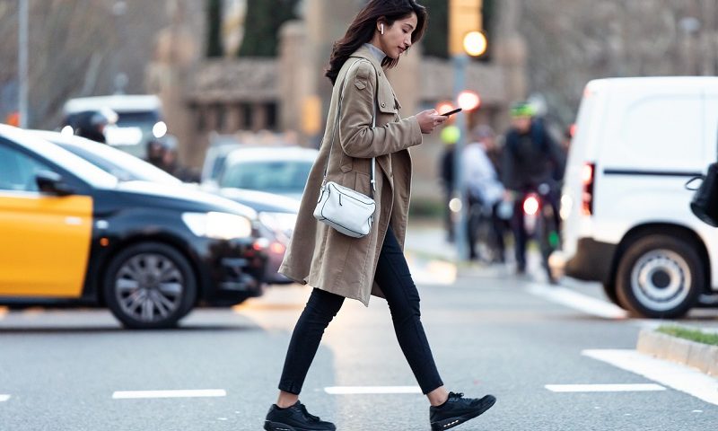 A woman crossing the road while using her phone