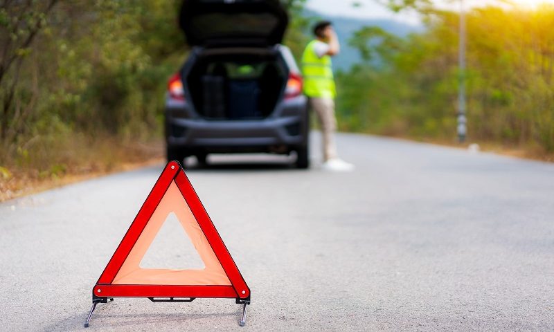 Breakdown triangle on road with broken down car