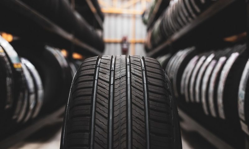 A new tire is placed on a tyre storage rack in a car workshop.