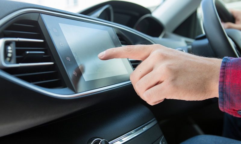 Man’s hand clicking on touch screen in car