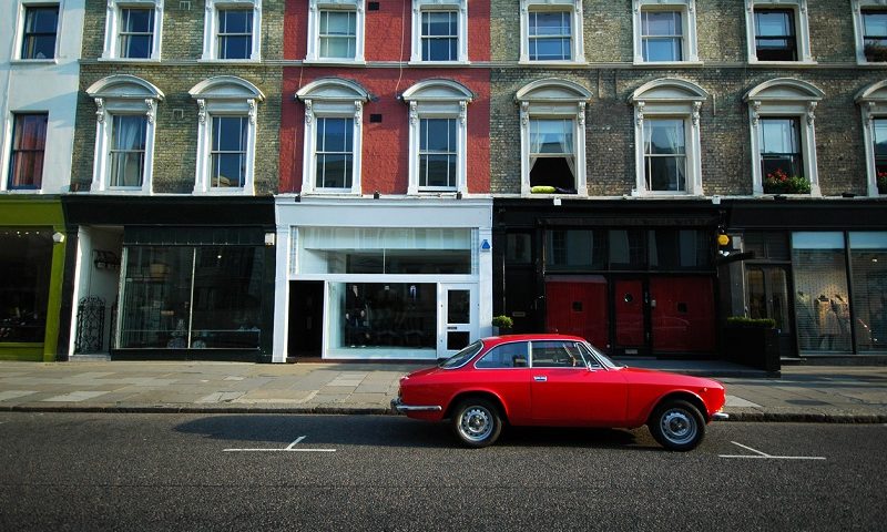 Old red sport car parked in front of a building in Notting Hill, London.