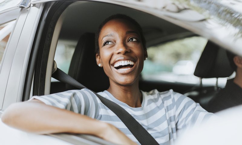 Woman smiling while driving a silver car